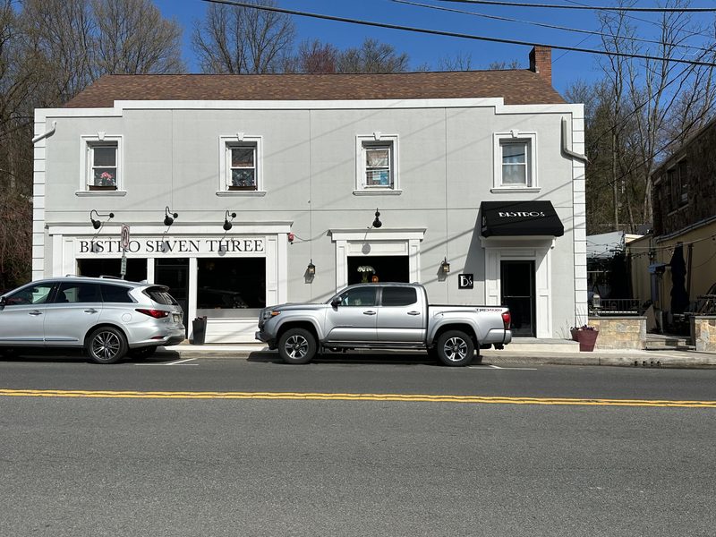 Bistro Seven Three storefront with black awnings and wall sconces