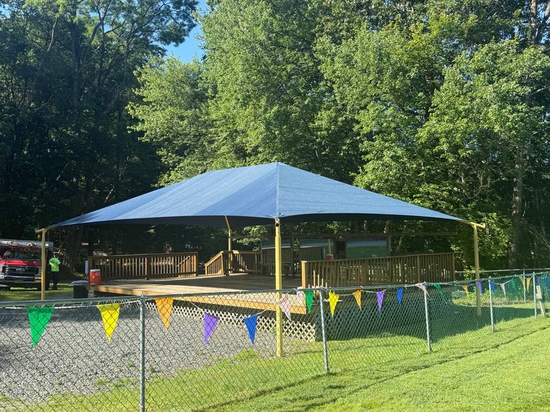 Blue shade canopy pavilion seen across a playing field
