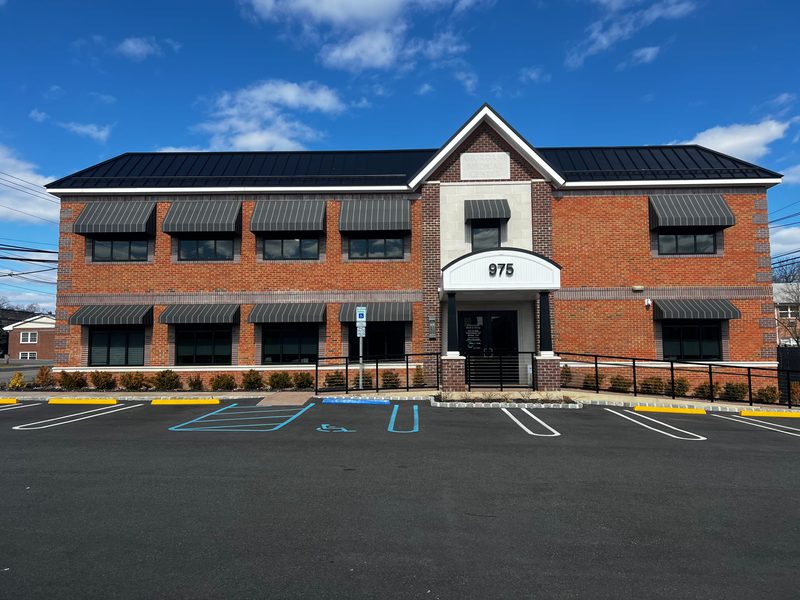 Brick office building with striped window awnings and entry canopy