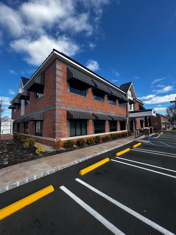 Corner view of a brick office building with striped window awnings